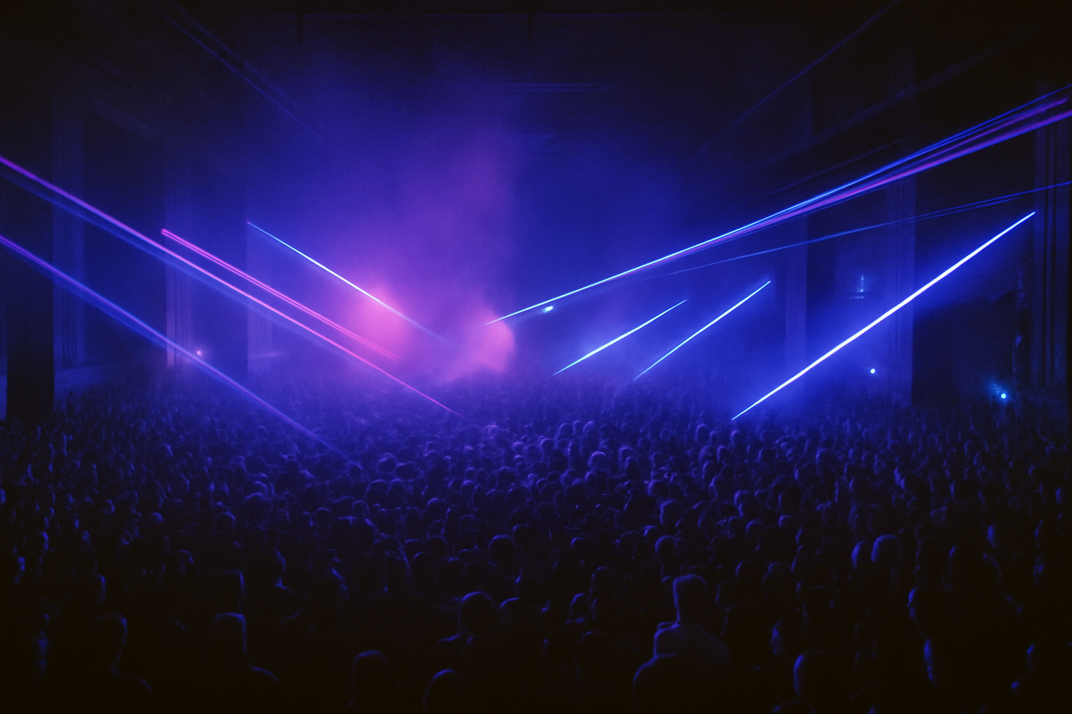 Foule dense dans une rave techno sous lasers bleus et pourpres, illustration de la necessite des bouchons d'oreilles