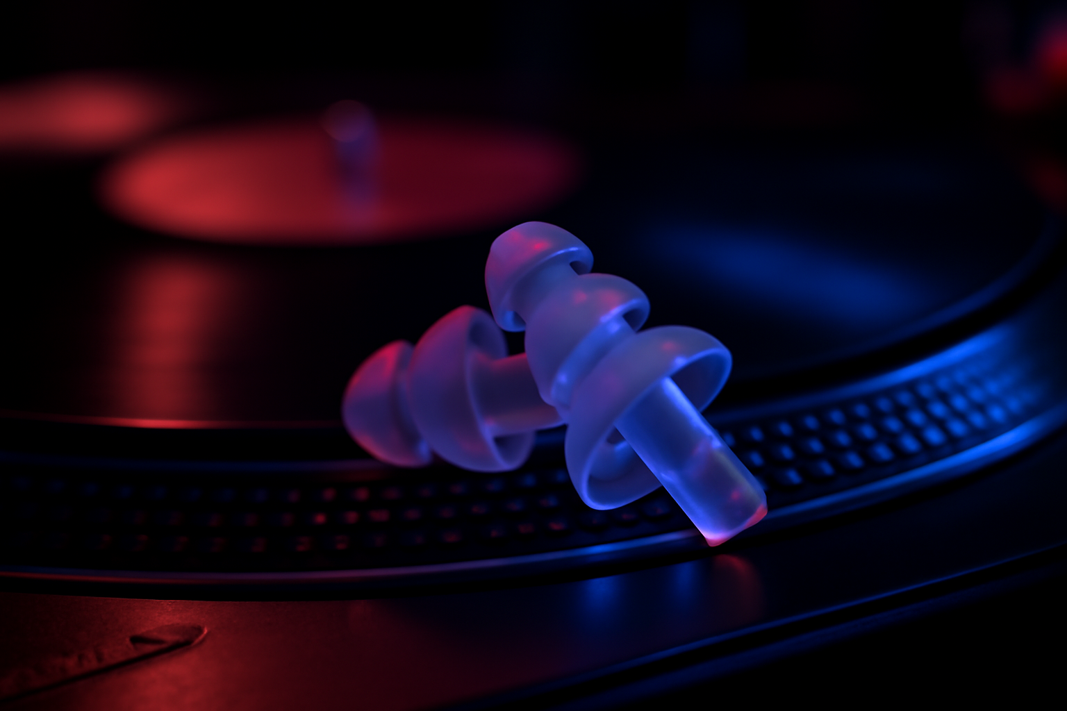Bouchons d'oreilles en silicone transparent design poses sur une platine Technics dans un club techno