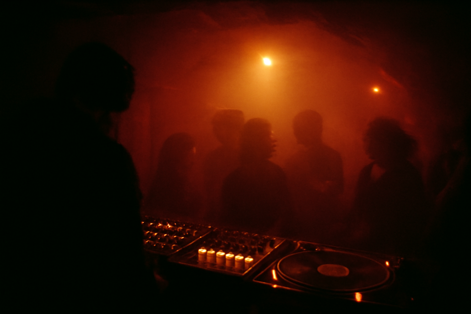 Ambiance d'un club techno intime a Bucarest, lumiere rouge et platines